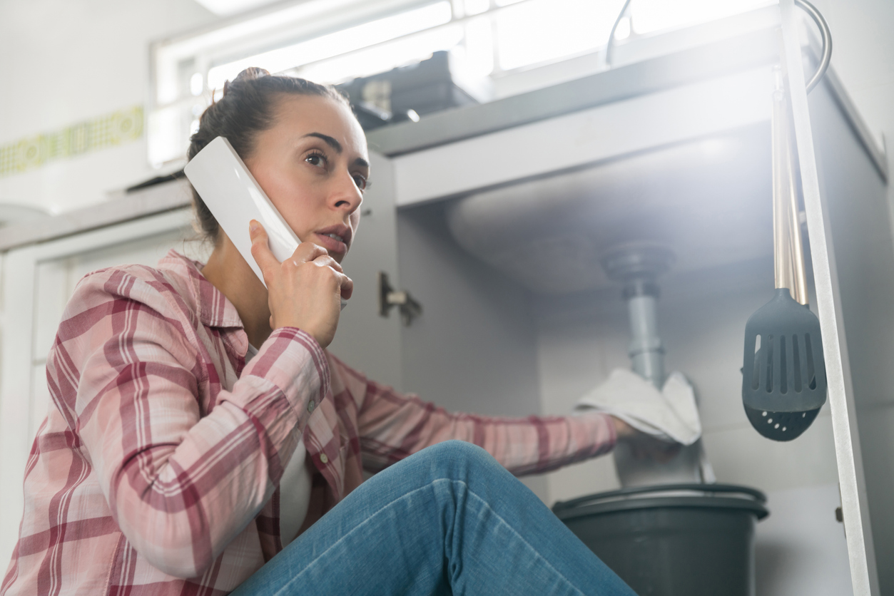 Woman Calling Plumber About Leaky Sink