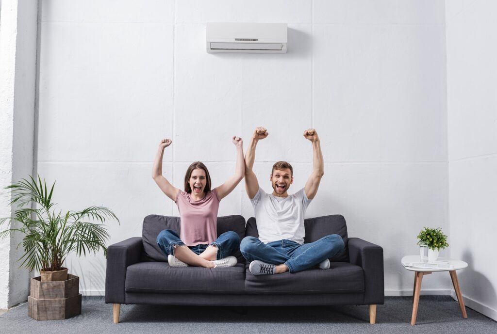 excited shouting couple at home with air conditioner after ac maintenance appointment