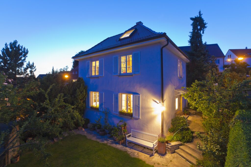 Flood lights shining from the corner of a beautiful home at dusk